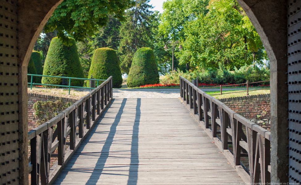 Drveni mostić koji vodi ka zelenilu u parku 
